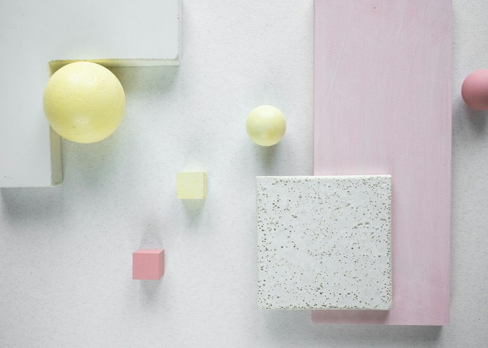 Pastel geometric shapes arranged creatively on a white textured surface.